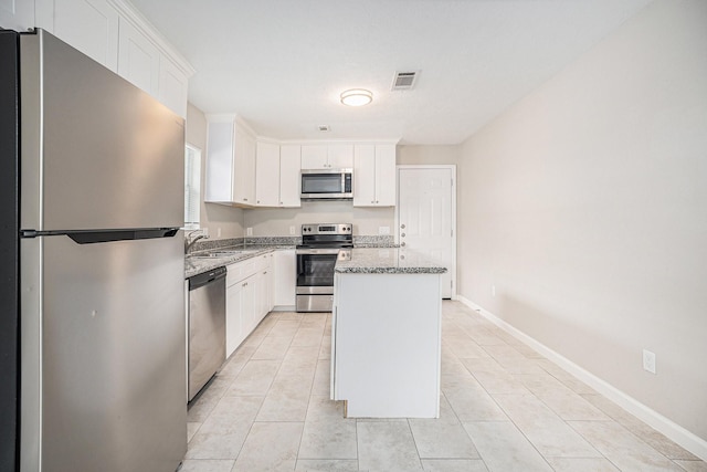 kitchen featuring visible vents, appliances with stainless steel finishes, a center island, a sink, and white cabinetry