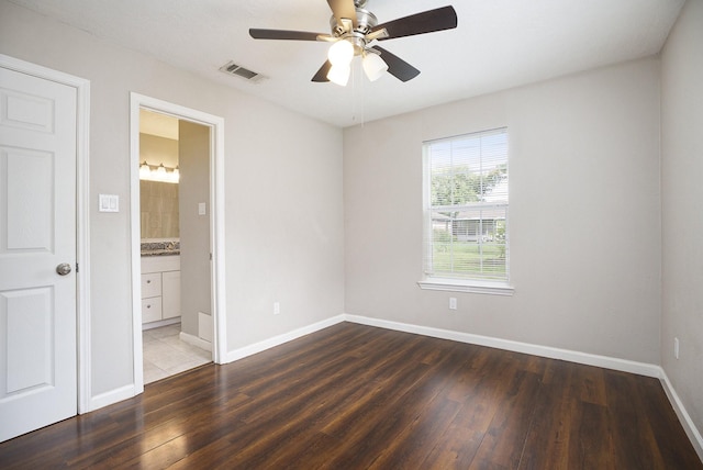 unfurnished bedroom featuring a ceiling fan, baseboards, wood finished floors, ensuite bathroom, and visible vents