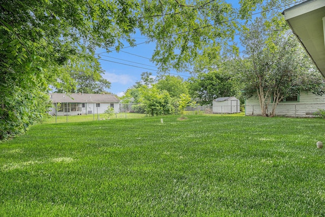 view of yard featuring a storage shed, fence, and an outbuilding