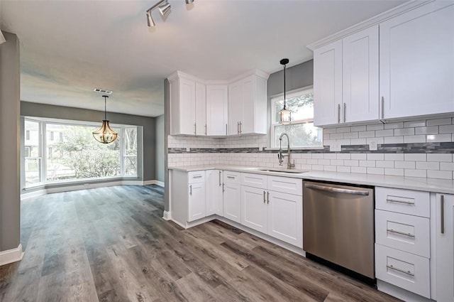 kitchen featuring stainless steel dishwasher, white cabinets, a sink, and tasteful backsplash