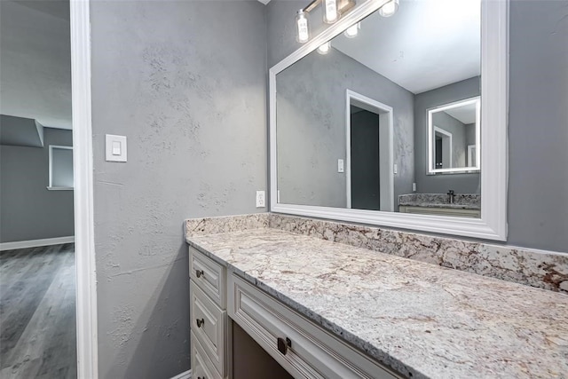 bathroom with vanity, baseboards, and wood finished floors