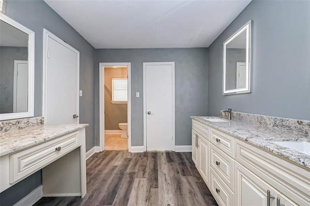 full bathroom with double vanity, toilet, a sink, and wood finished floors