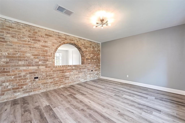 unfurnished room featuring visible vents, baseboards, brick wall, and a chandelier