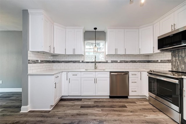 kitchen with decorative backsplash, appliances with stainless steel finishes, a sink, light countertops, and white cabinetry