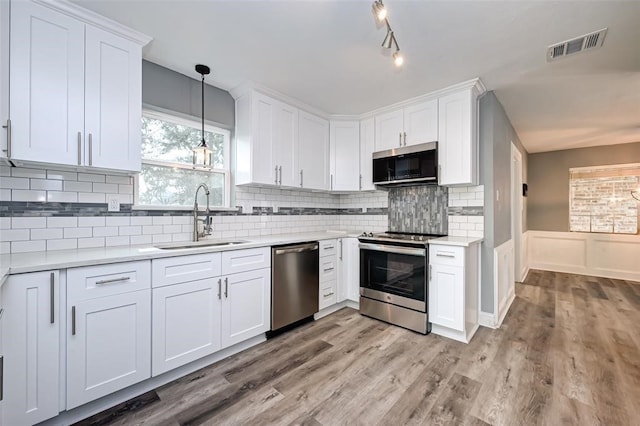 kitchen featuring appliances with stainless steel finishes, a sink, light countertops, white cabinetry, and visible vents