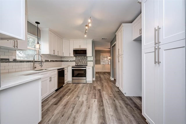 kitchen with a sink, white cabinetry, appliances with stainless steel finishes, and light wood-style flooring