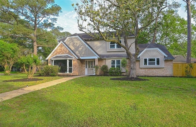 view of front of house with fence, brick siding, and a front yard