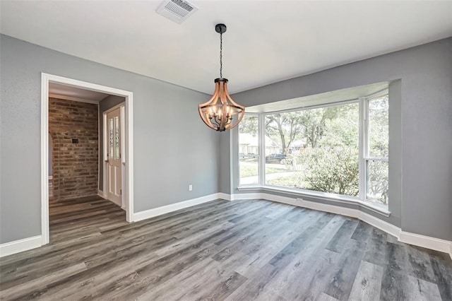 unfurnished dining area with baseboards, a wealth of natural light, a notable chandelier, and visible vents