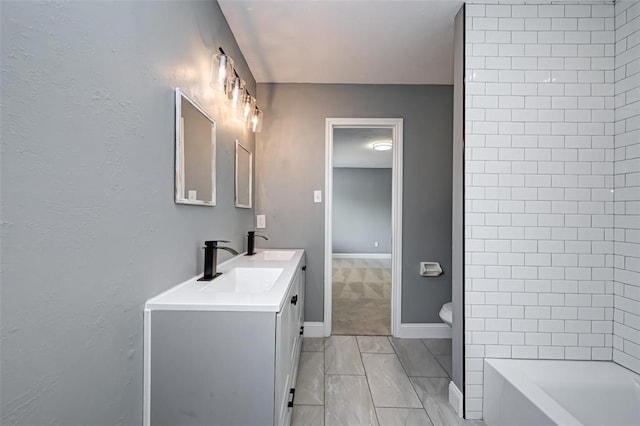 bathroom with double vanity, a sink, baseboards, and toilet