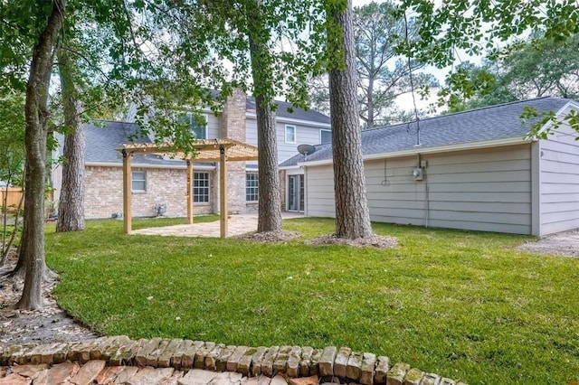rear view of property with a patio area, a yard, a pergola, and roof with shingles