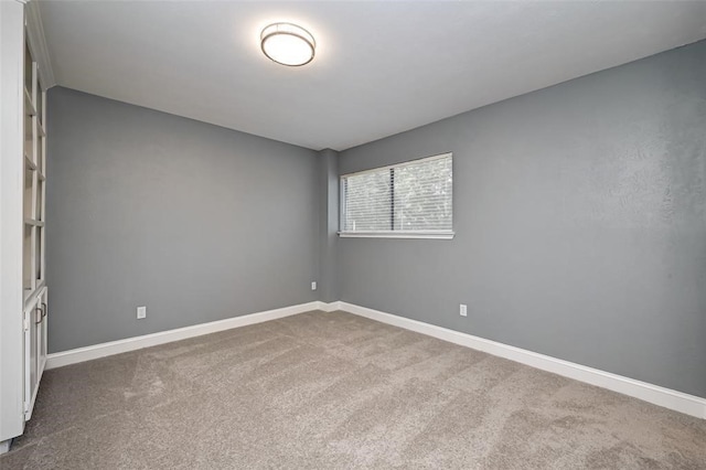 unfurnished room with baseboards and dark carpet