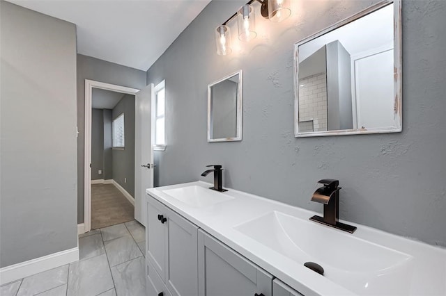 full bath featuring baseboards, a sink, and double vanity
