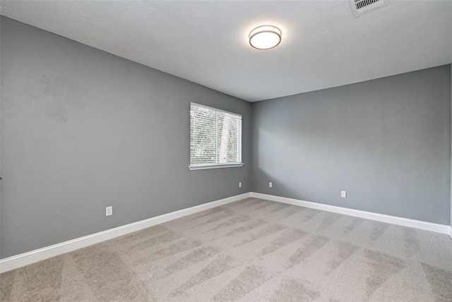 empty room featuring light colored carpet, baseboards, and visible vents