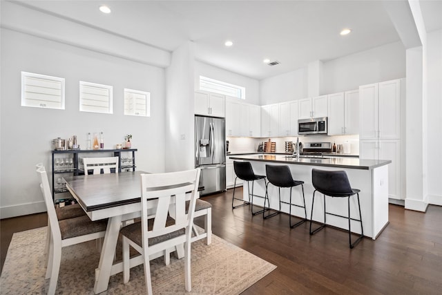 1023 Roberts St, Houston, TX 77003 - kitchen featuring stainless steel appliances, a breakfast bar area, a kitchen island with sink, white cabinetry, and dark wood-style flooring