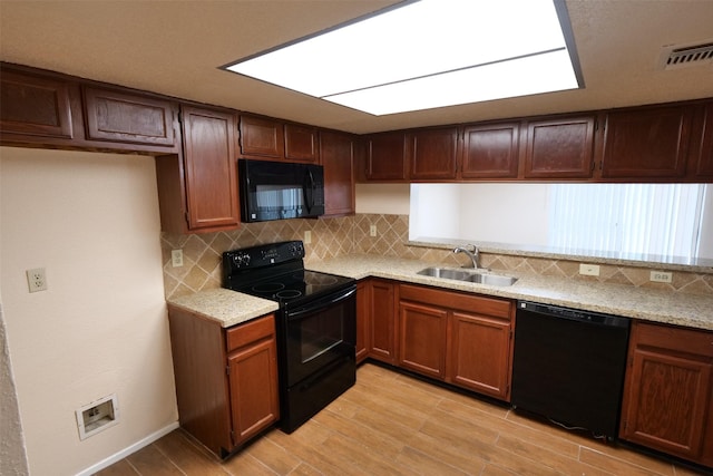 kitchen with light wood-style floors, a sink, decorative backsplash, and black appliances