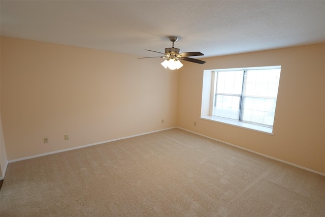 unfurnished room featuring light colored carpet, baseboards, and ceiling fan