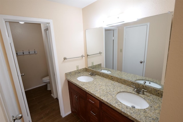 full bathroom with toilet, baseboards, a sink, and wood finished floors