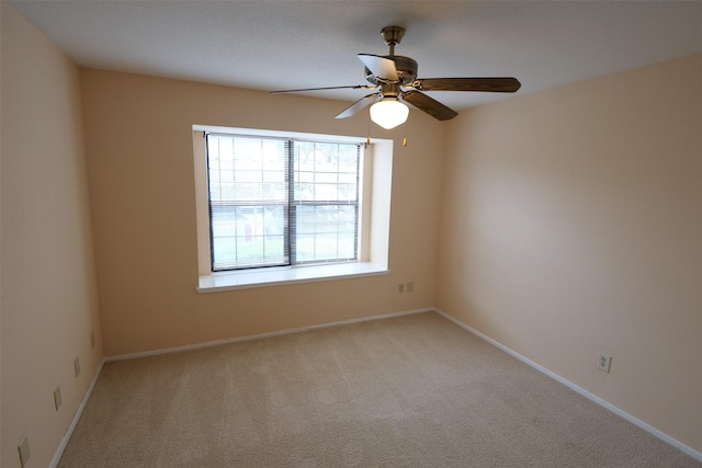 unfurnished room featuring baseboards, light colored carpet, and ceiling fan