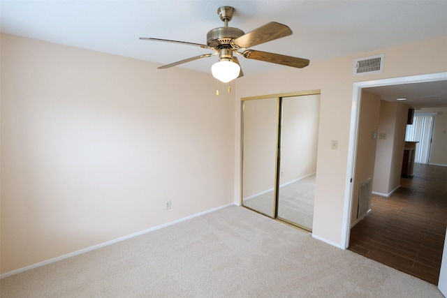 unfurnished bedroom featuring carpet floors, baseboards, a closet, and visible vents