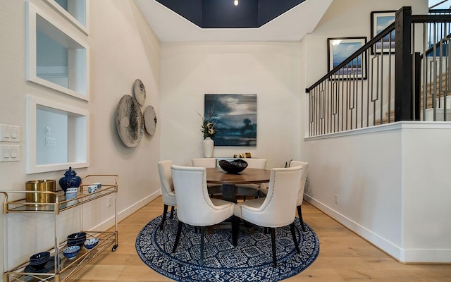 dining room with baseboards, wood finished floors, and stairway