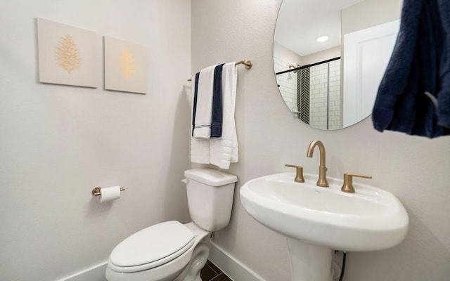 bathroom with a tile shower, a sink, toilet, tile patterned floors, and baseboards