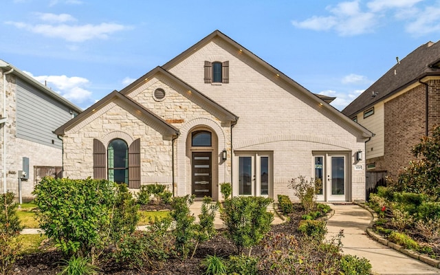 french country inspired facade with stone siding and brick siding