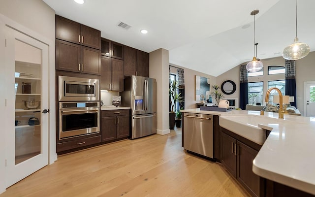 kitchen featuring light countertops, stainless steel appliances, light wood-style flooring, and dark brown cabinets