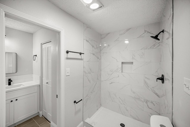 full bath with vanity, a shower stall, and a textured ceiling