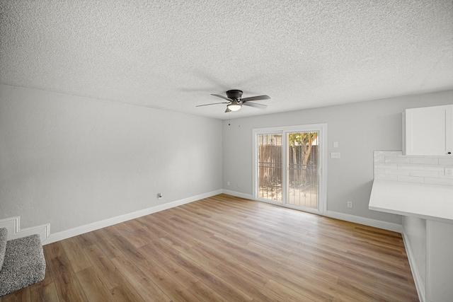unfurnished living room featuring baseboards, ceiling fan, a textured ceiling, and light wood-style flooring