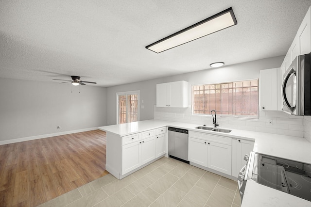 kitchen featuring ceiling fan, a textured ceiling, appliances with stainless steel finishes, a sink, and a peninsula