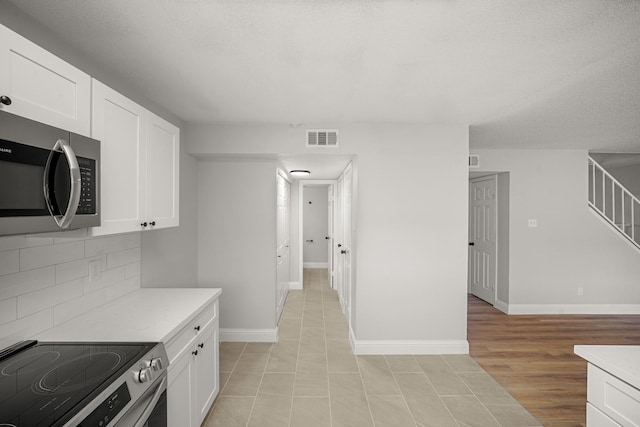 kitchen with visible vents, light countertops, white cabinetry, and stainless steel appliances
