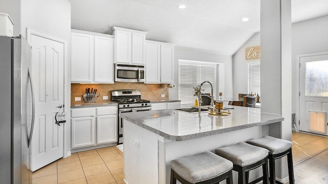 kitchen featuring white cabinets, a sink, backsplash, vaulted ceiling, and stainless steel appliances