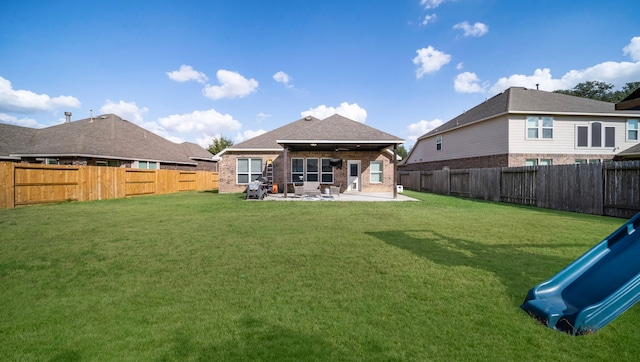 rear view of house with a lawn, a fenced backyard, and a patio area