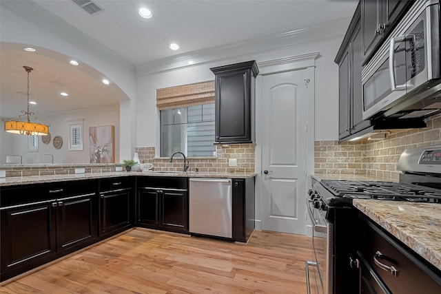 kitchen featuring light stone countertops, appliances with stainless steel finishes, a sink, visible vents, and ornamental molding