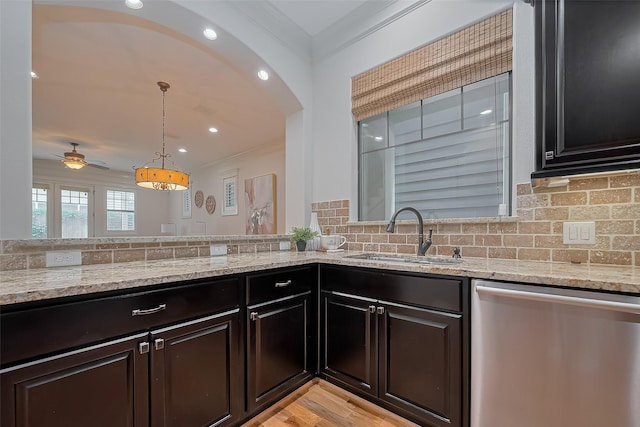 kitchen featuring light stone counters, ornamental molding, a sink, and dishwasher