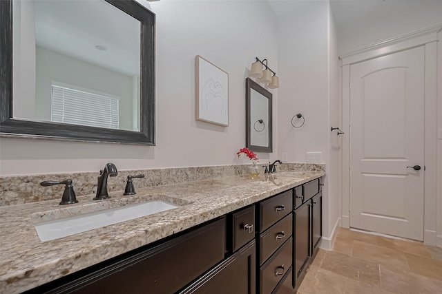 full bath with double vanity, a sink, and stone finish floor