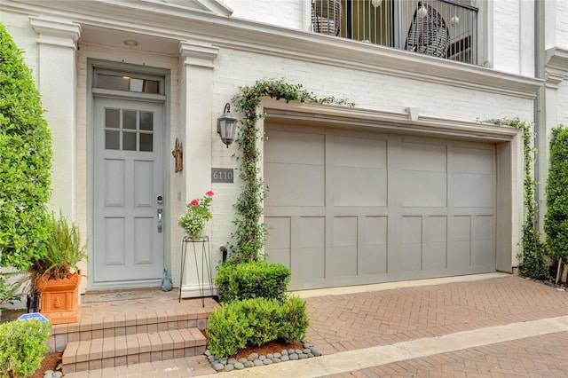 view of exterior entry featuring a garage and decorative driveway