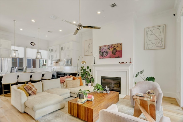 living room with visible vents, a glass covered fireplace, ceiling fan, recessed lighting, and light wood-type flooring