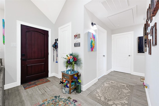 foyer with baseboards, lofted ceiling, wood finished floors, and visible vents