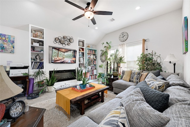 living area featuring a glass covered fireplace, wood finished floors, lofted ceiling, ceiling fan, and recessed lighting