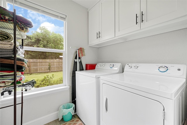 washroom with baseboards, washing machine and dryer, and cabinet space