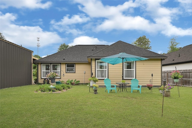back of property with a yard, fence, and roof with shingles