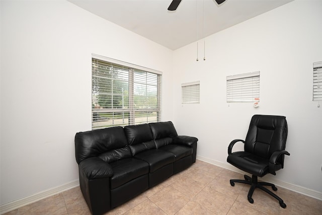 living area featuring baseboards, ceiling fan, and light tile patterned flooring