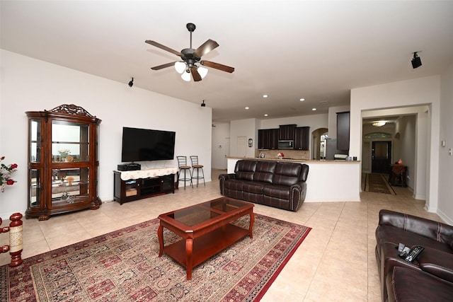 living area with arched walkways, a ceiling fan, recessed lighting, and light tile patterned flooring