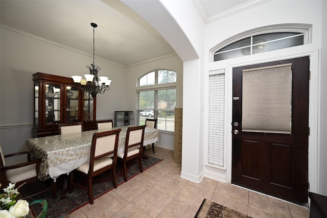 foyer entrance featuring crown molding, light tile patterned flooring, arched walkways, a chandelier, and baseboards