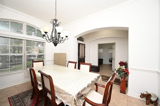 dining area featuring crown molding, arched walkways, a chandelier, baseboards, and light tile patterned floors