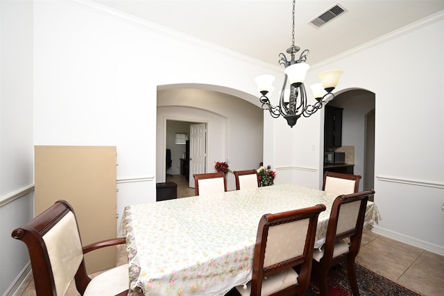 dining space with visible vents, arched walkways, light tile patterned floors, an inviting chandelier, and ornamental molding