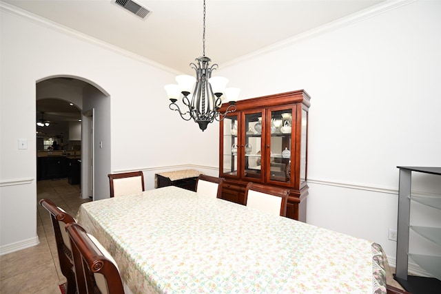 dining space with arched walkways, tile patterned floors, ceiling fan with notable chandelier, visible vents, and ornamental molding