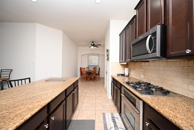 kitchen featuring a ceiling fan, backsplash, dark brown cabinets, light tile patterned floors, and stainless steel appliances