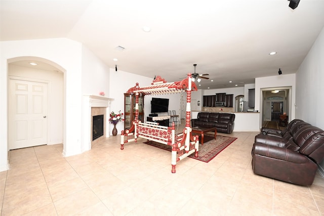 living room with a ceiling fan, arched walkways, lofted ceiling, a glass covered fireplace, and recessed lighting